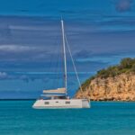 a sailboat floating in the ocean near a rocky shore