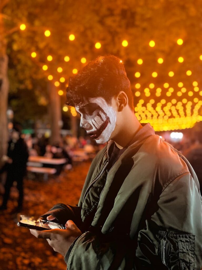 Man with a Death Mask Painting on his Face Using his Smart Phone